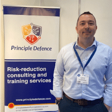 Jim in front of a Principle Defence Banner
